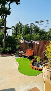 a wooden bench sitting in a garden with green grass at บ้านประภัสราคม โฮมสเตย์ นครสวรรค์ in Ban Ko Ta Thep
