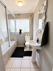 a bathroom with a sink and a tub and a toilet at Zhantique Guest House 2- Unit 3 in Boksburg