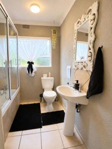 a bathroom with a toilet and a sink and a mirror at Zhantique Guest House 2- Unit 3 in Boksburg