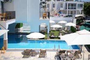 a pool with chairs and umbrellas next to a building at Quatro Life Hotel in Bodrum City