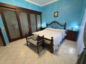 a bedroom with a bed and a chair and blue walls at Villa Aurea in Avola +19 photos