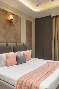 a bedroom with a large bed with pink and grey pillows at Alaya Stays Luxora Suites, Golf Course Rd near galleria in Gurgaon