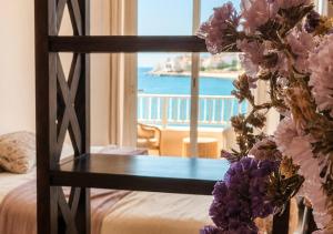 a room with a bed and a glass table with flowers at Mareluna Luxury Accomodation in Lampedusa