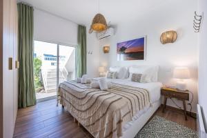 a white bedroom with a large bed and a window at Casa Alvor in Alvor