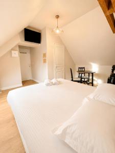 a bedroom with two white beds and a table at Onyx Green in Saint-Aignan