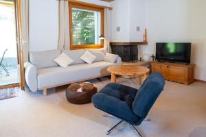 a living room with a couch and a chair and a table at Garden apartment with mountain views & barbecue in Lenz