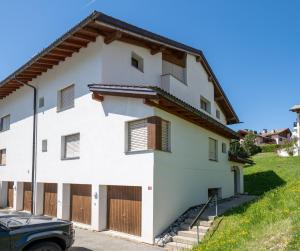 a white house with wooden doors and a car parked in front at Garden apartment with mountain views & barbecue in Lenz