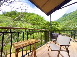 a wooden balcony with a table and a chair at Suối Mộc Ecostay - Mộc Châu in Mộc Châu