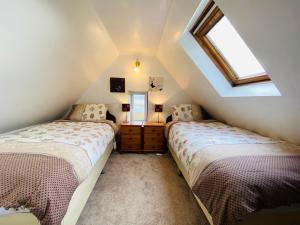 a attic bedroom with two beds and a window at The Lodge Ellary in Lochgilphead