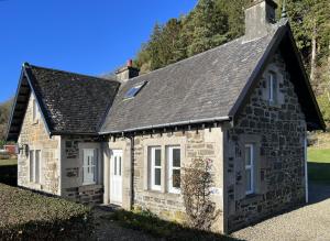 a stone cottage with a black roof at The Lodge Ellary in Lochgilphead