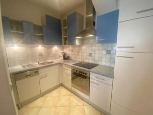 a kitchen with white appliances and blue cabinets at Saskia Apartments in Ortisei