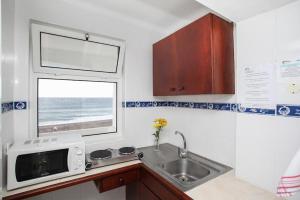 a kitchen with a sink and a microwave and a window at Aparthotel Barracuda in Ponta Delgada