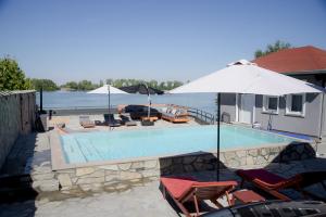 a swimming pool with chairs and an umbrella at Aurum Etno & Spa in Smederevo