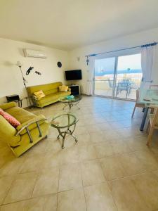 a living room with a yellow couch and a glass table at Sea View Pool 2BR Esentepe in Kalogrea