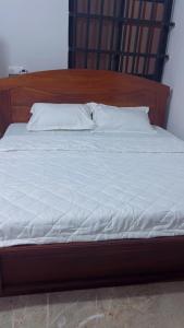 a large bed with a wooden headboard and white sheets at Elite Solutions Apartments in Ouéga