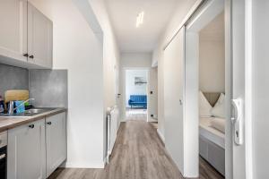 a kitchen with white cabinets and a hallway with a bed at Kleine Seeperle in Quickborn
