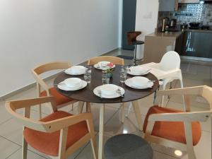 a dining room table and chairs with plates and bowls at Metropol Summer Cozy Suite in Bukit Mertajam