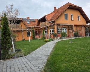 a house with a brick walkway in front of a yard at Susann Vendégház in Szigetmonostor