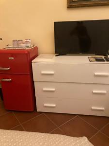 a television on top of a dresser with a red refrigerator at Villa Fontana in Capannori