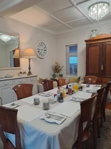 a dining room with a table and chairs and a clock at Meerlin Guest House in Queenstown