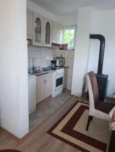 a kitchen with white cabinets and a chair and a sink at Vrba in Gacko