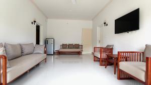 a living room with a couch and a flat screen tv at Estate IV - Saffron Suite - Tea Estate Stay in Vythiri