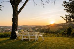 a table and chairs under a tree with the sunset at Casa Adele - 10 min from the sea! in Carignano