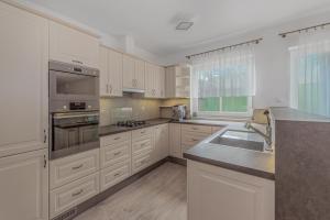 a kitchen with white cabinets and stainless steel appliances at Suchohrdelská VILLA u vinařství LAHOFER - RD NOVOSTAVBA v Suchohrdly u Znojma - 2 - 10 osob, 2 apartments in Suchohrdly
