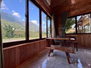 a room with a bench and a table with windows at Zay Riverside House in Tả Van