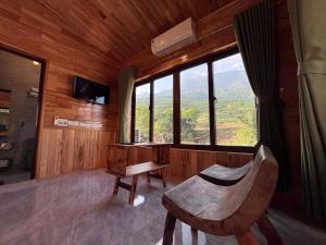 a room with a chair and a table and a window at Zay Riverside House in Tả Van