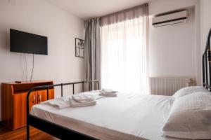 a bedroom with a bed with white sheets and a window at Summerland Lake View Apartament in Mamaia