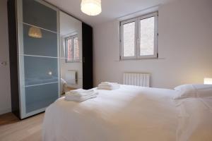 a white bedroom with a large bed and two windows at Appartement Plaisance in Lille