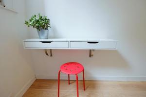a white desk with a red stool under it at Appartement Plaisance in Lille