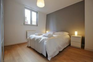 a bedroom with a white bed and a window at Appartement Plaisance in Lille