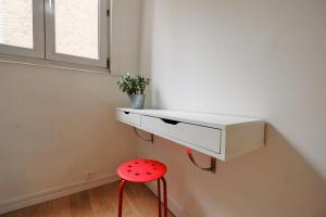 a red stool sitting under a white shelf with a window at Appartement Plaisance in Lille +15 photos