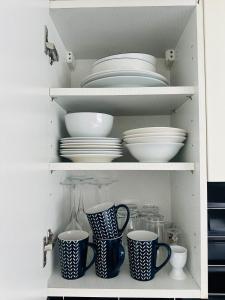 a cupboard filled with plates and bowls and dishes at Aquila House in Saint Helier Jersey +2 photos