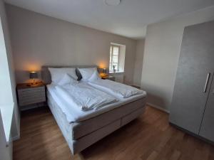 a bedroom with a bed with white sheets and two lamps at Linden's Apartments in Ayl