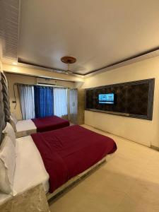 a bedroom with two beds and a tv on the wall at Roshan Residency in Matheran