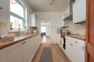 a kitchen with white cabinets and a wooden floor at Spacious 3 Bed In Rugby in Rugby