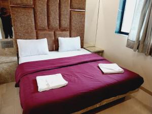 a bedroom with a large bed with two towels on it at Roshan Residency in Matheran +4 photos