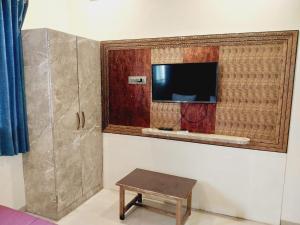 a room with a tv on a wall with a table at Roshan Residency in Matheran
