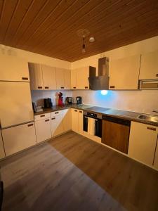 a large kitchen with white cabinets and a wooden ceiling at Tannennest in Seewald