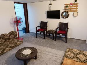 a living room with two chairs and a flat screen tv at Rousan House in Um Qeis