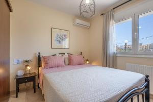a bedroom with a bed with pink pillows and a window at Villa Melenia 1 in Agia Pelagia