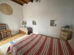 a bedroom with a large bed and a chair at Evnomia Cycladic Home from 1912 in Mélanes
