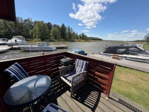 a deck with chairs and a table and a boat at Horns Skärgårdscamping in Nyköping