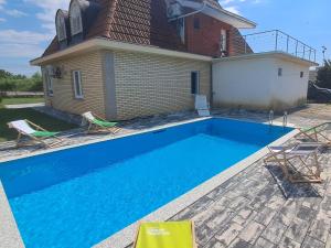 a swimming pool with two chairs and a house at Villa Alpine in Valjiosi