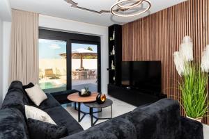a living room with a black couch and a television at Amfi Luxury Villa 4BR with Private Pool by Villa Mana Gers in Sarakinádhon