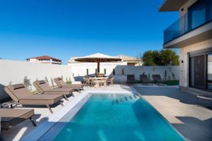 a pool with chairs and a table and an umbrella at Amfi Luxury Villa 4BR with Private Pool by Villa Mana Gers in Sarakinádhon