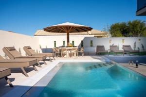 a pool with chairs and a table and an umbrella at Amfi Luxury Villa 4BR with Private Pool by Villa Mana Gers in Sarakinádhon